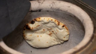 タンドール窯の内壁で焼かれるナン