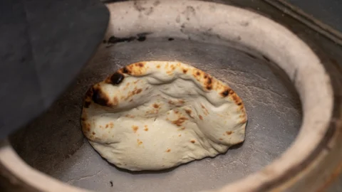 タンドール窯の内壁で焼かれるナン