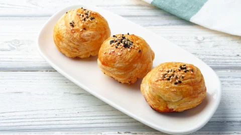 ゴマをのせた黄金色の焼き包みパン（胡椒餅のイメージ）